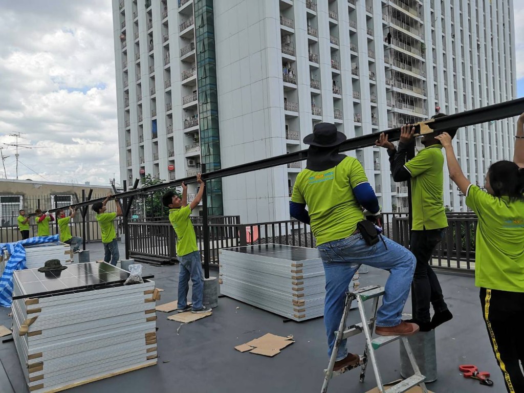 Thai Solar Power installation team lifting solar panels to a rooftop for a hybrid solar project in Thailand