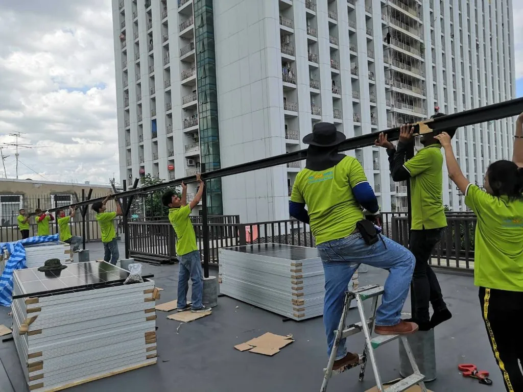 Thai Solar Power installation team lifting solar panels to a rooftop for a hybrid solar project in Thailand